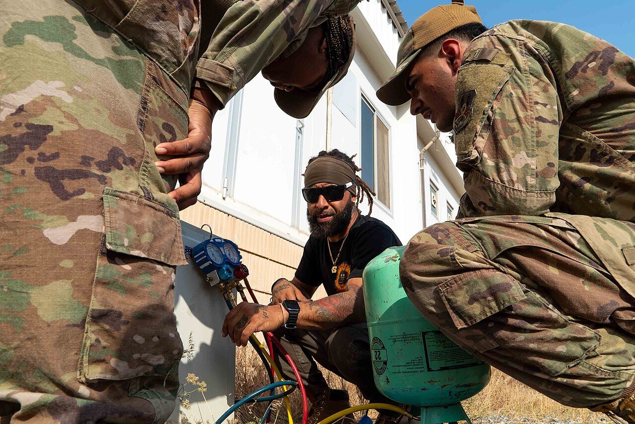 Three HVAC-R technicians adding refrigerant to a mini-split unit